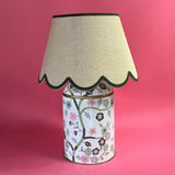 a tole chinoiserie lamp painted with pink and green blossom motifs and a green trimmed scalloped rattan lampshade. 