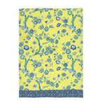 A yellow chinoiserie tea towel with a blue cherry blossom motif and a blue lattice pattern border against a white background. 