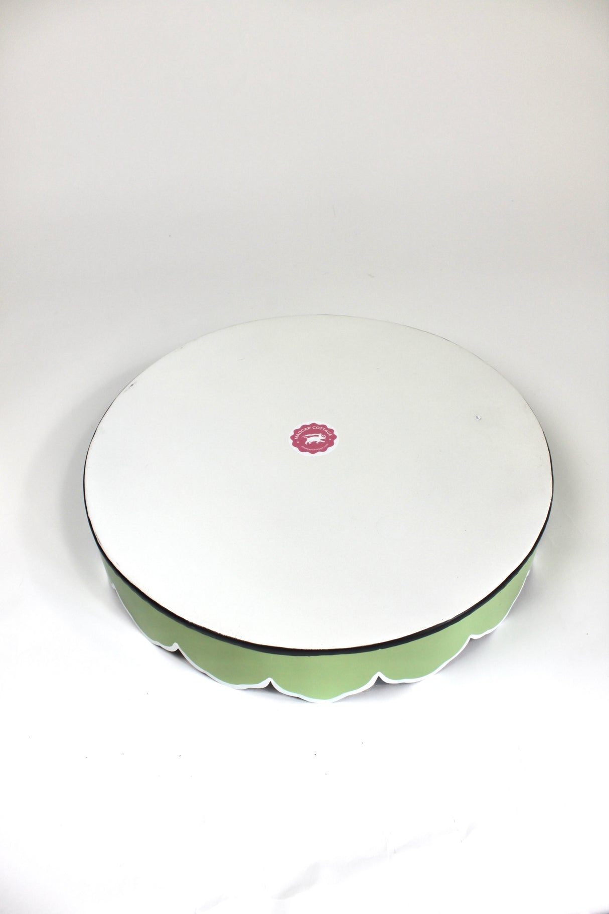 The plain white reverse side of a tole metal, scallop edged pink and green chinoiserie tray from madcap cottage.