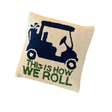 A white golf pillow with a blue golf cart and green text that reads THIS IS HOW WE ROLL