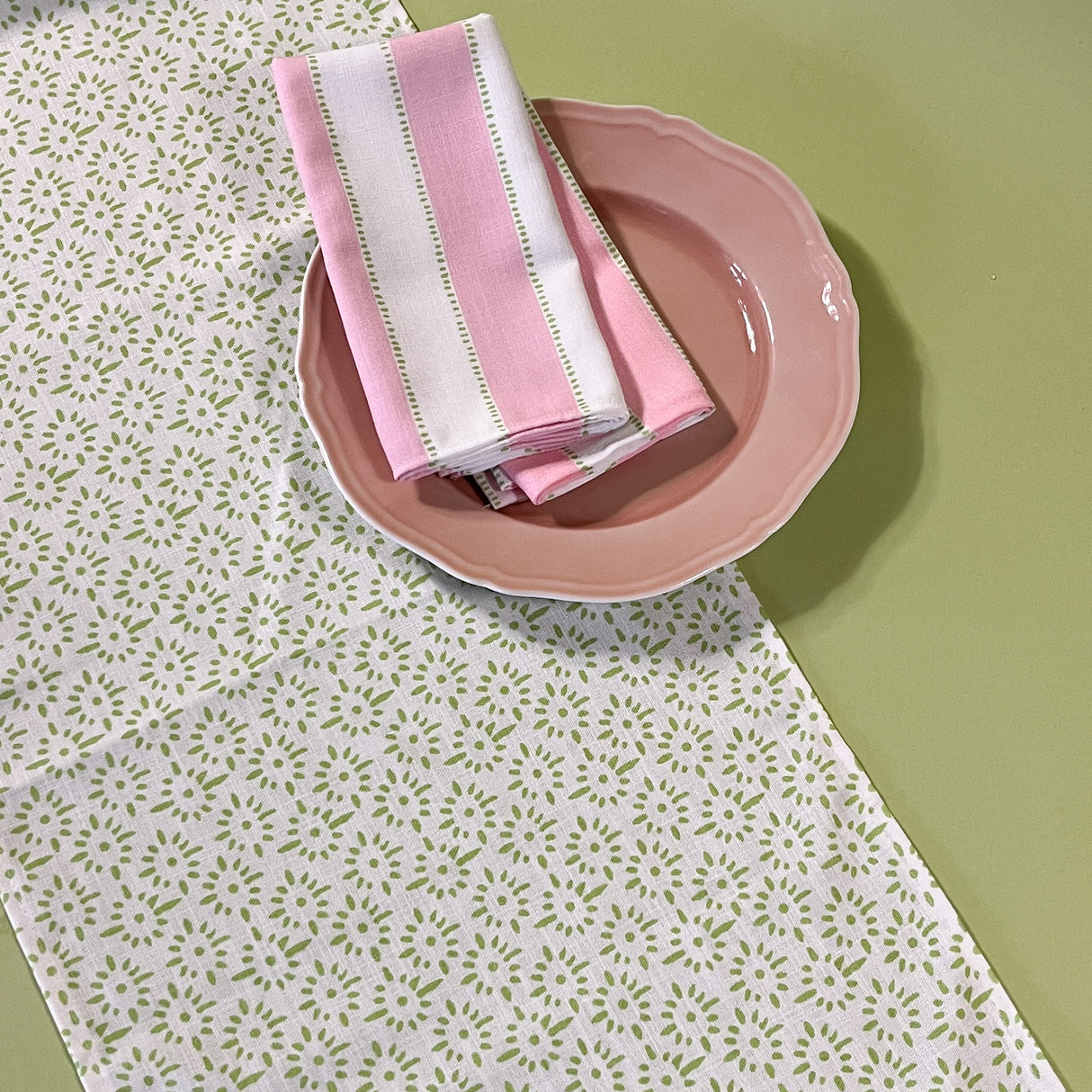 Detail view of white Toujours Provence cloth table runner with a celery green block print motif.