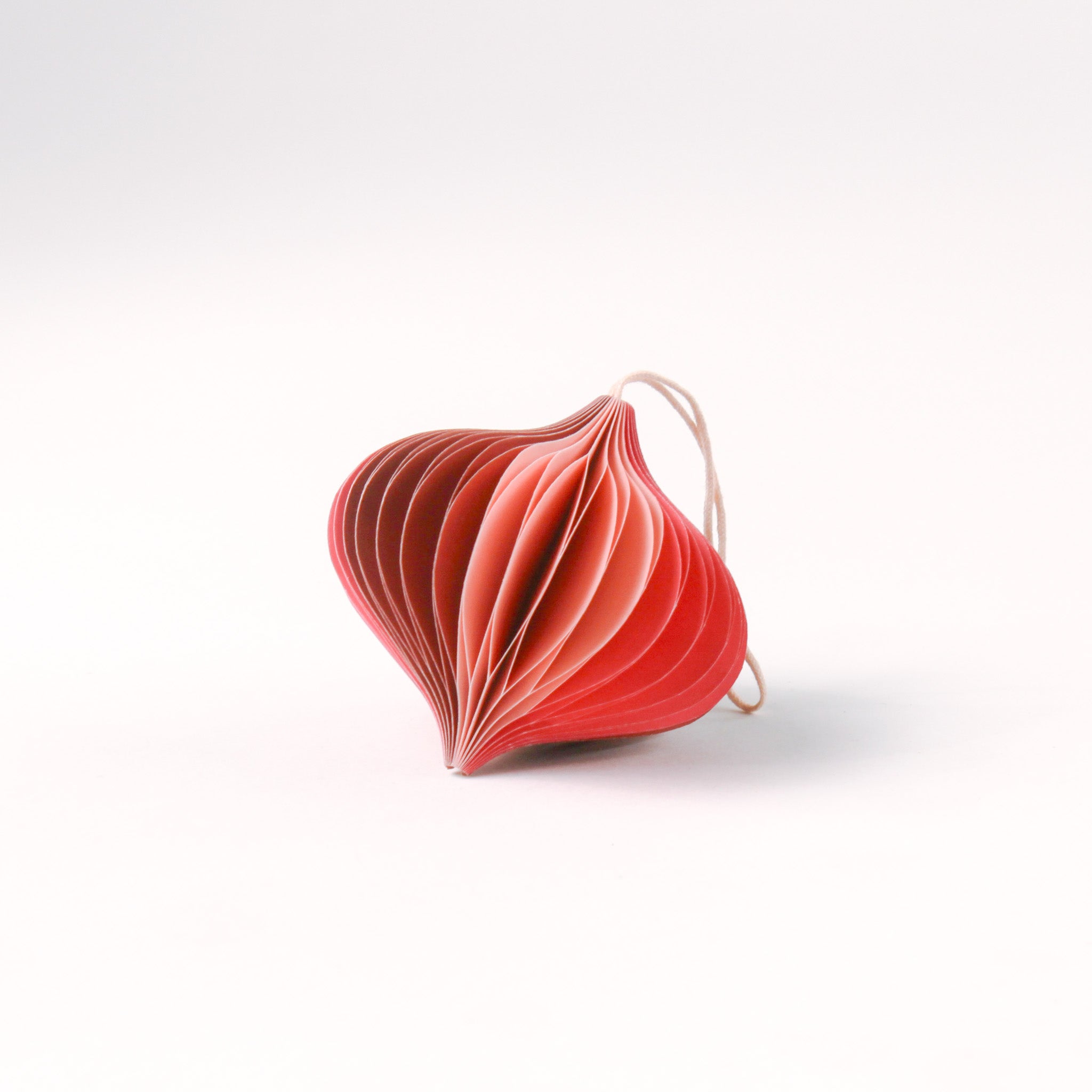 Close-up of pink folded paper Christmas ornaments in assorted bulb and teardrop shapes with hanging strings