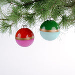 Two colorful Christmas ornaments hanging on a tree branch.