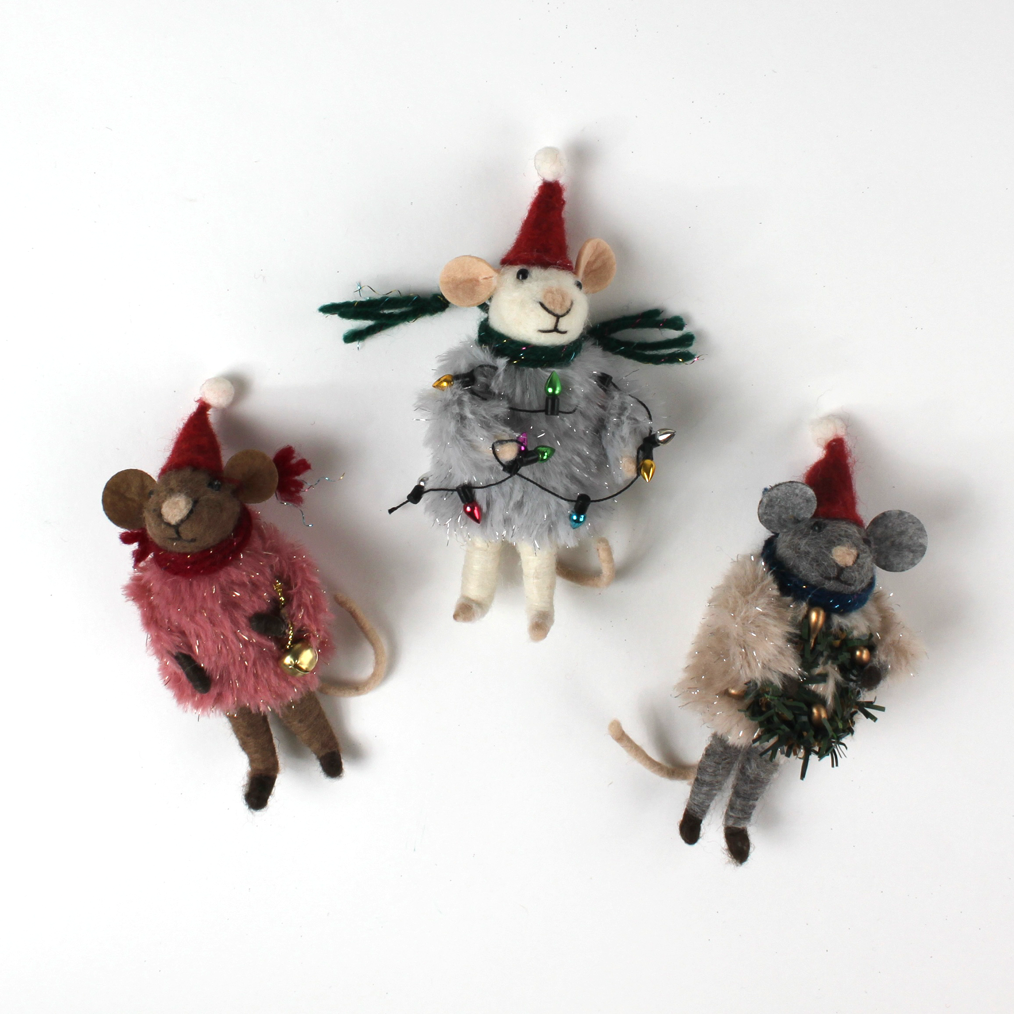 Three festive felt mouse ornaments dressed in fuzzy holiday outfits and Santa hats, holding Christmas decorations like string lights, a wreath, and a gold bell.
