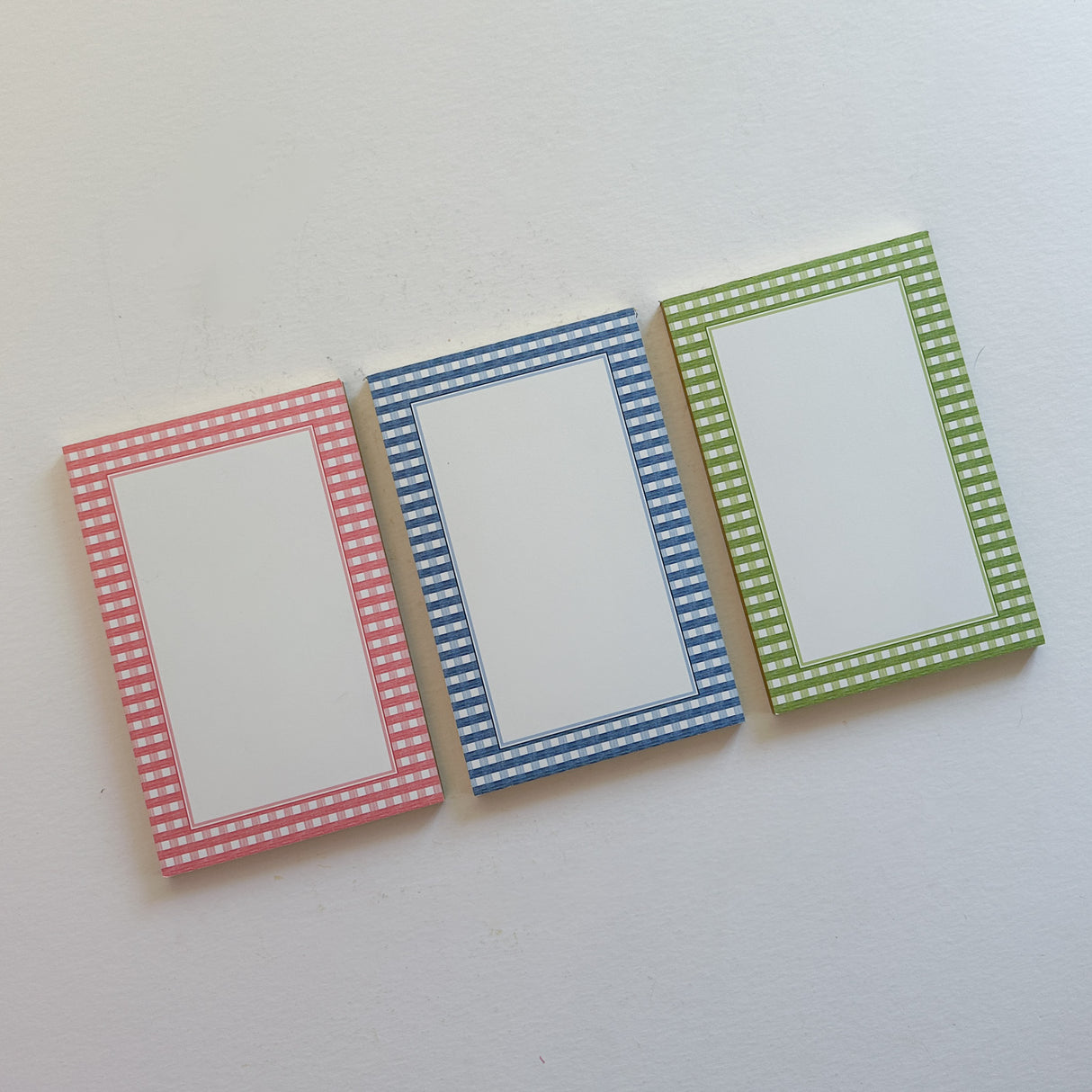 three gingham bordered notepads