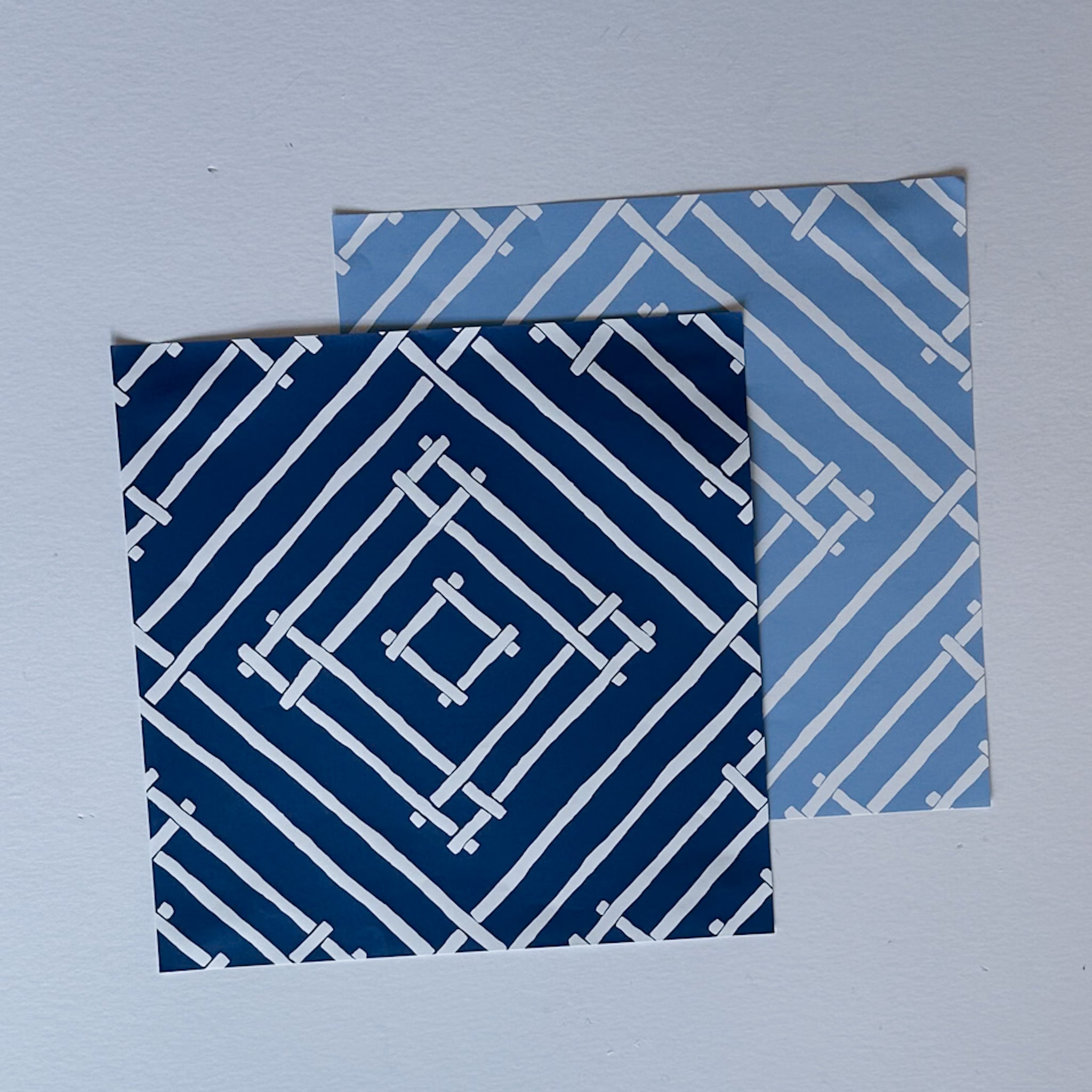 two square blue paper placemats with a white bamboo trellis design called "Island House" from Madcap Cottage.