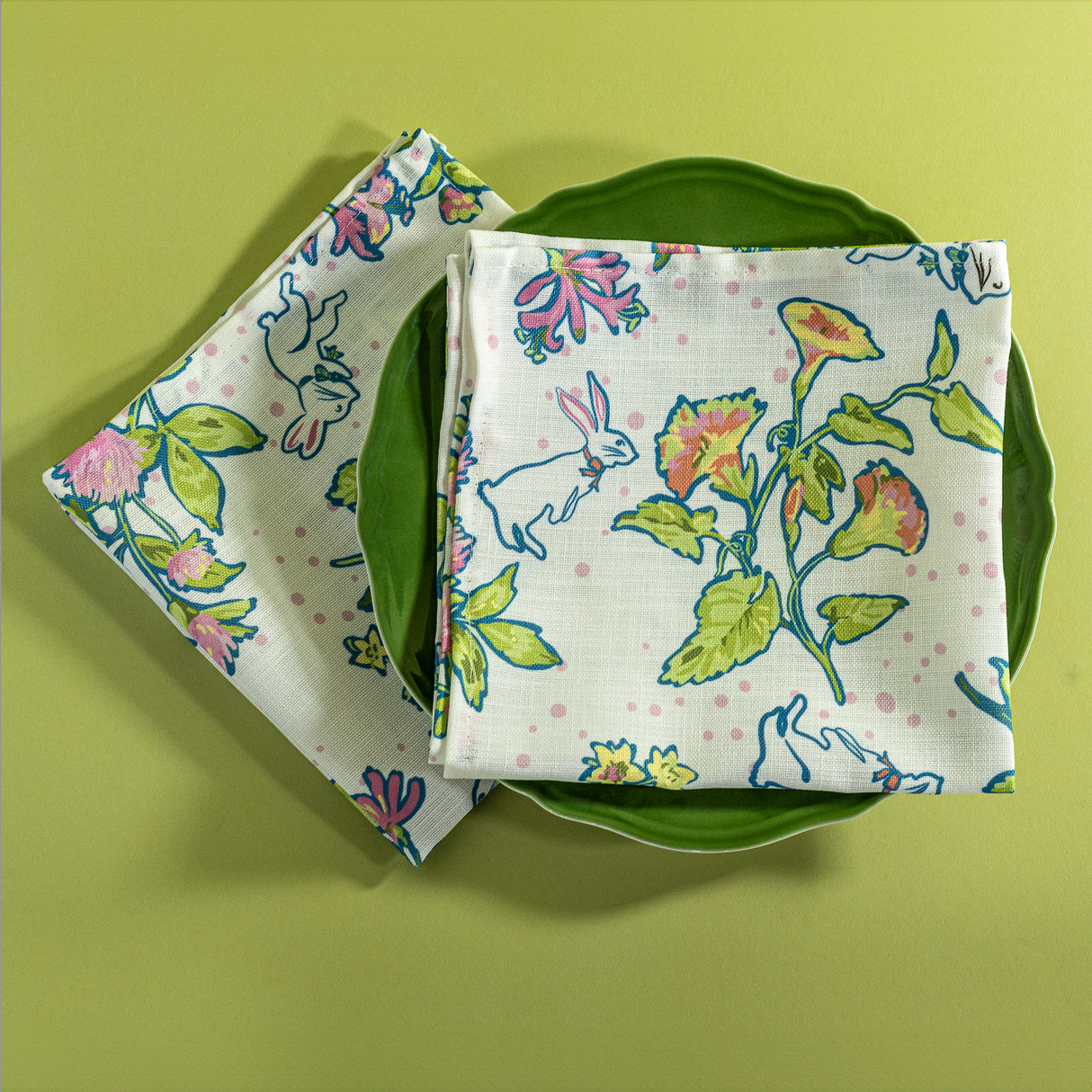 A multicolor bunny and strawberry print fabric Easter napkin on a green plate.