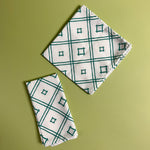 two white and green cloth dinner napkins in Island House Small trellis print madcap cottage fabric against a light green background

