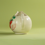A white vintage strawberry pitcher with strawberry motifs decorating the side