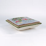 Square decorative pillow with a hooked design featuring a yellow crane standing among green leaves and pink water lilies on a light blue background with a butterfly flying nearby.