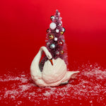 a White Vintage Arched-Neck Ceramic Swan w/Pink Glitter Christmas Tree Centerpiece against a red background. 