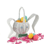 white wicker bunny Easter basket filled with colorful eggs and pink filler on white background