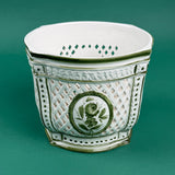 White ceramic cachepot with green trim and lattice design featuring a green floral medallion on the front