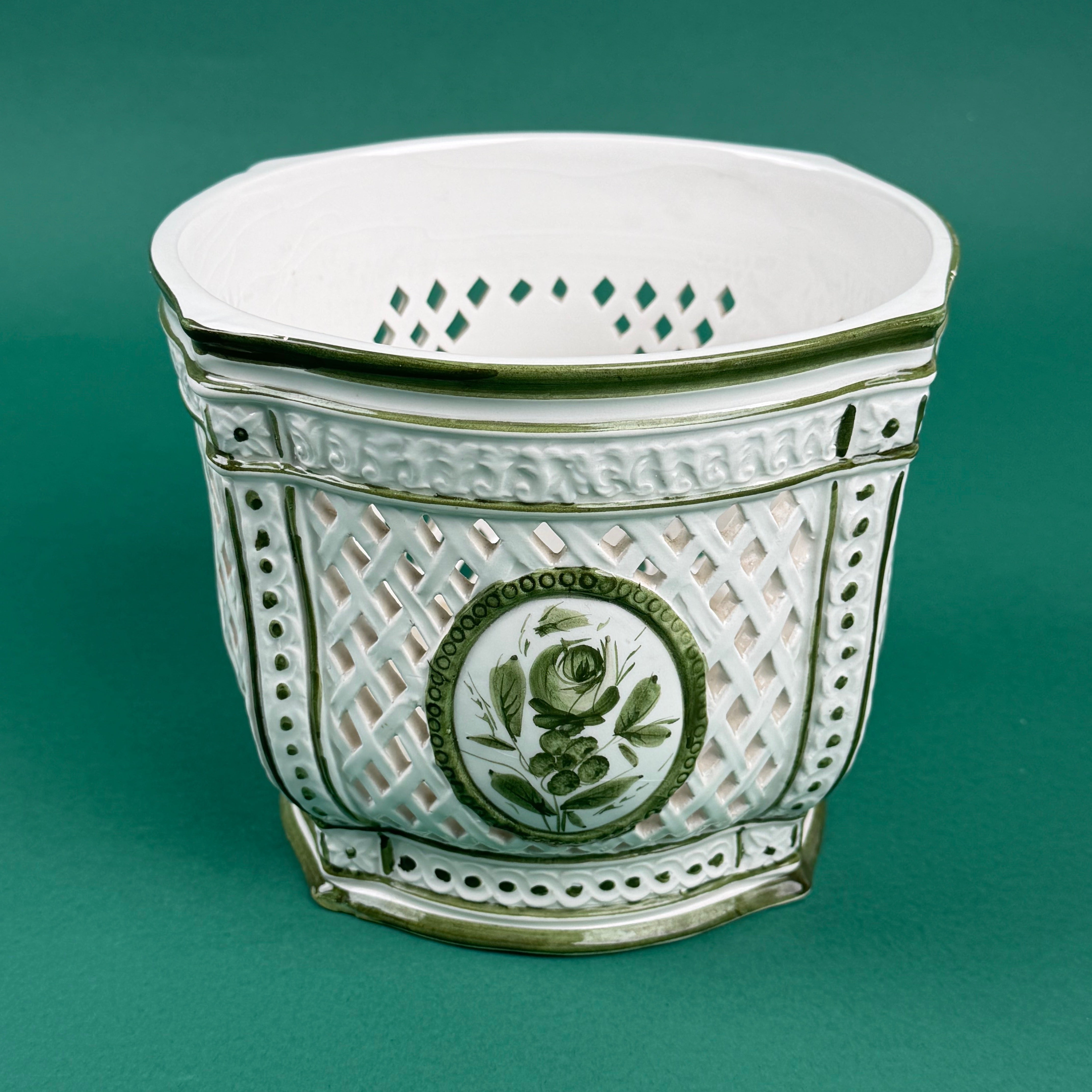 White ceramic cachepot with green trim and lattice design featuring a green floral medallion on the front