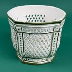 White ceramic lattice planter with green trim on a green background