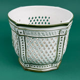 White ceramic lattice planter with green trim on a green background