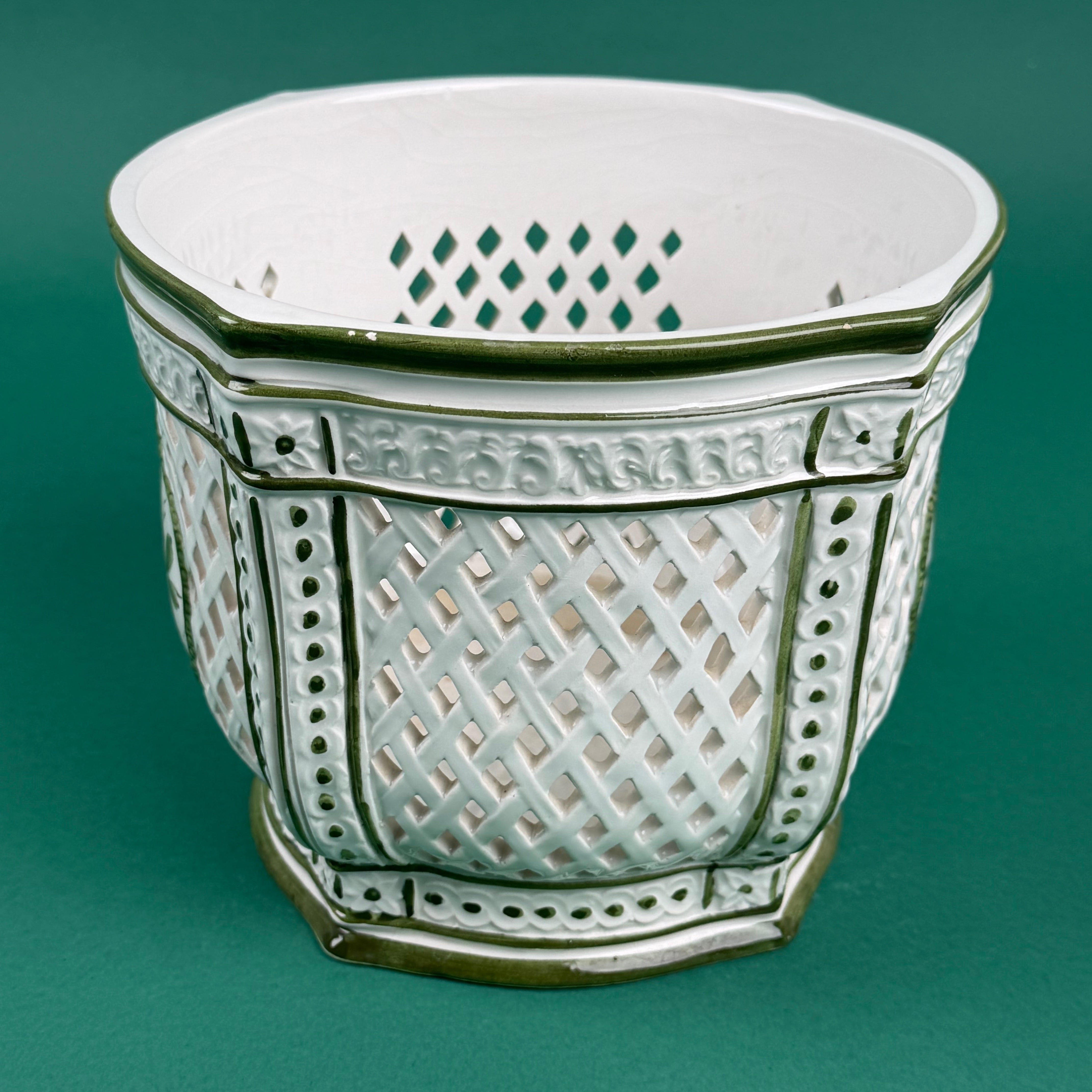 White ceramic lattice planter with green trim on a green background