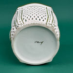 White ceramic lattice planter with green trim on a green background