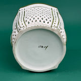 White ceramic lattice planter with green trim on a green background