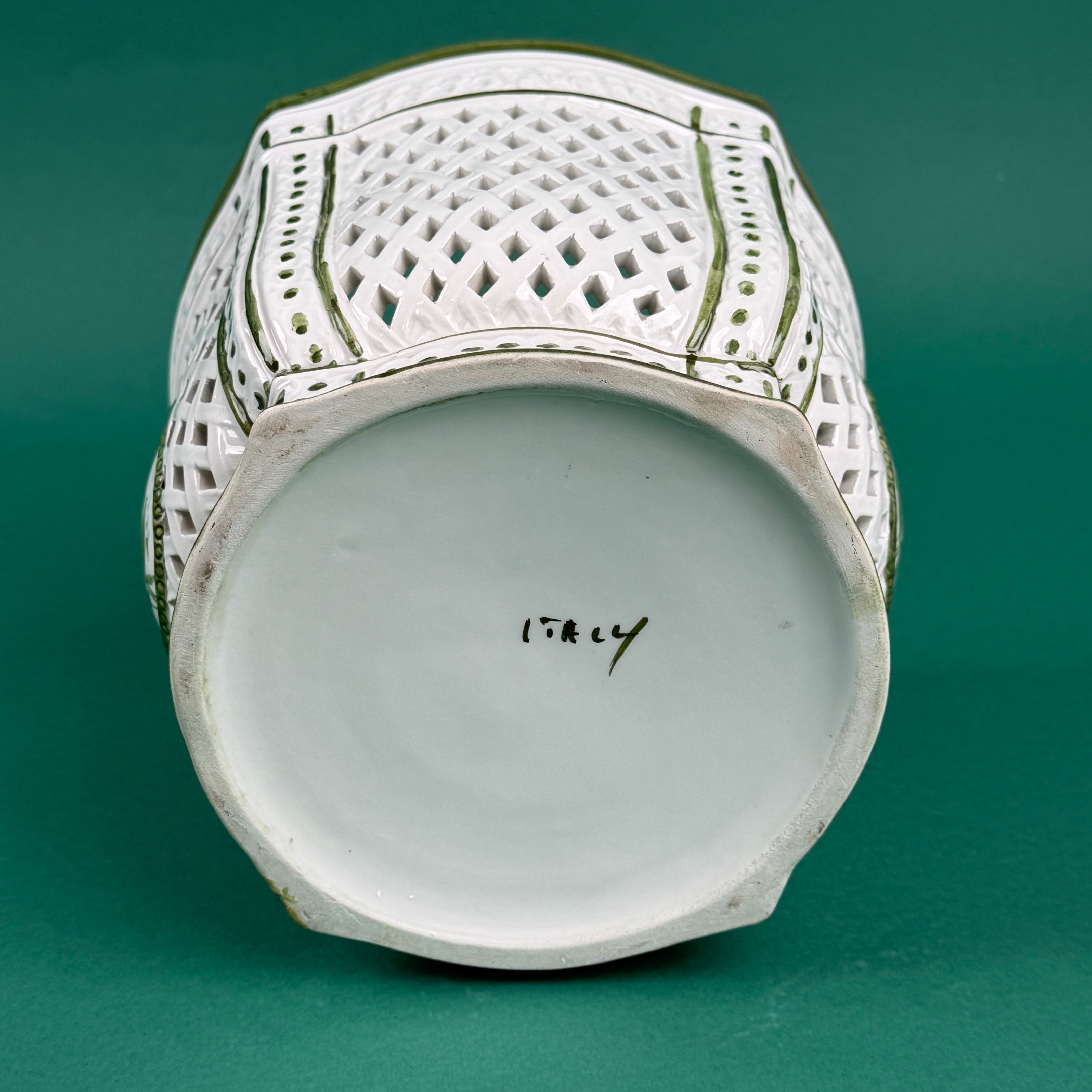 White ceramic lattice planter with green trim on a green background