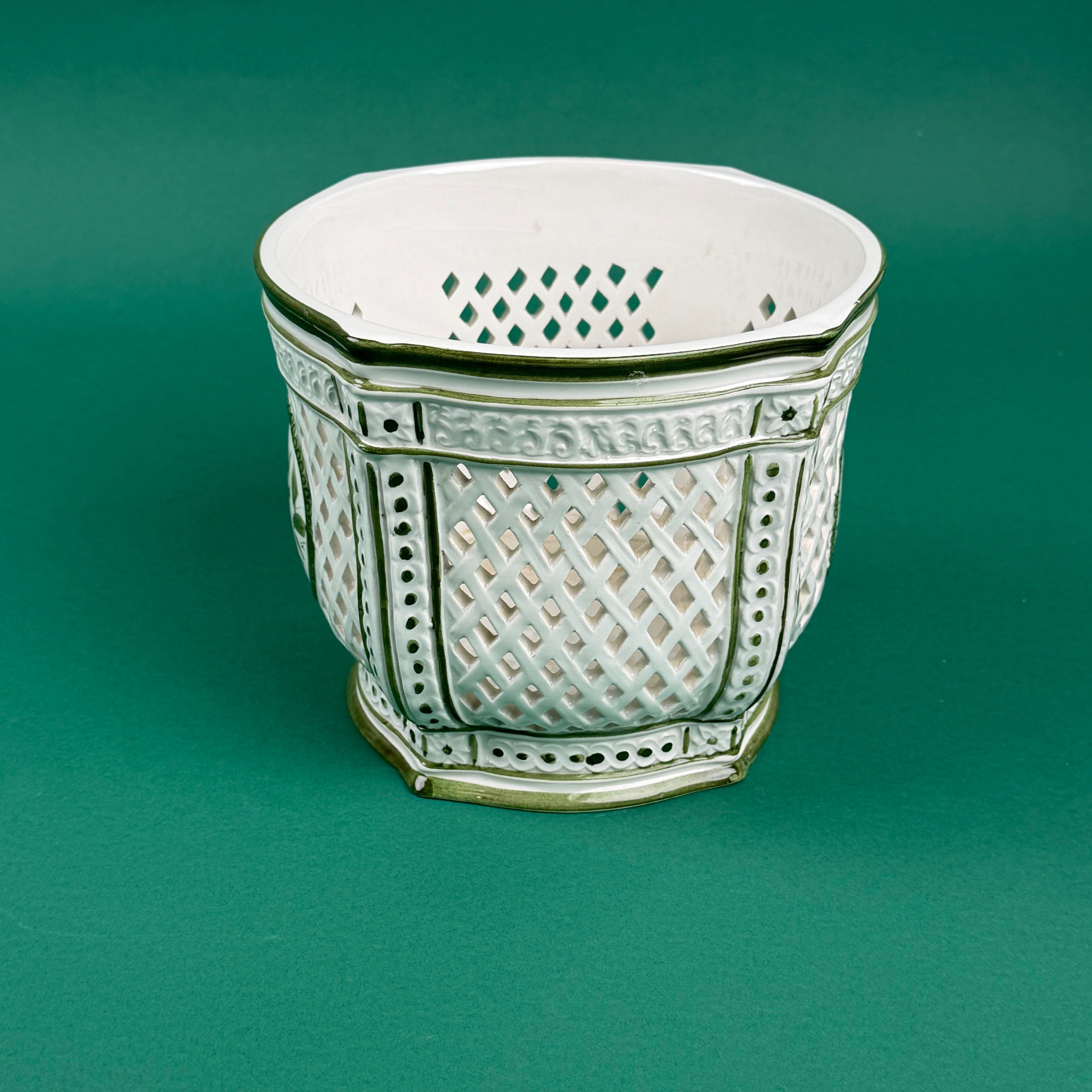 White ceramic lattice planter with green trim on a green background
