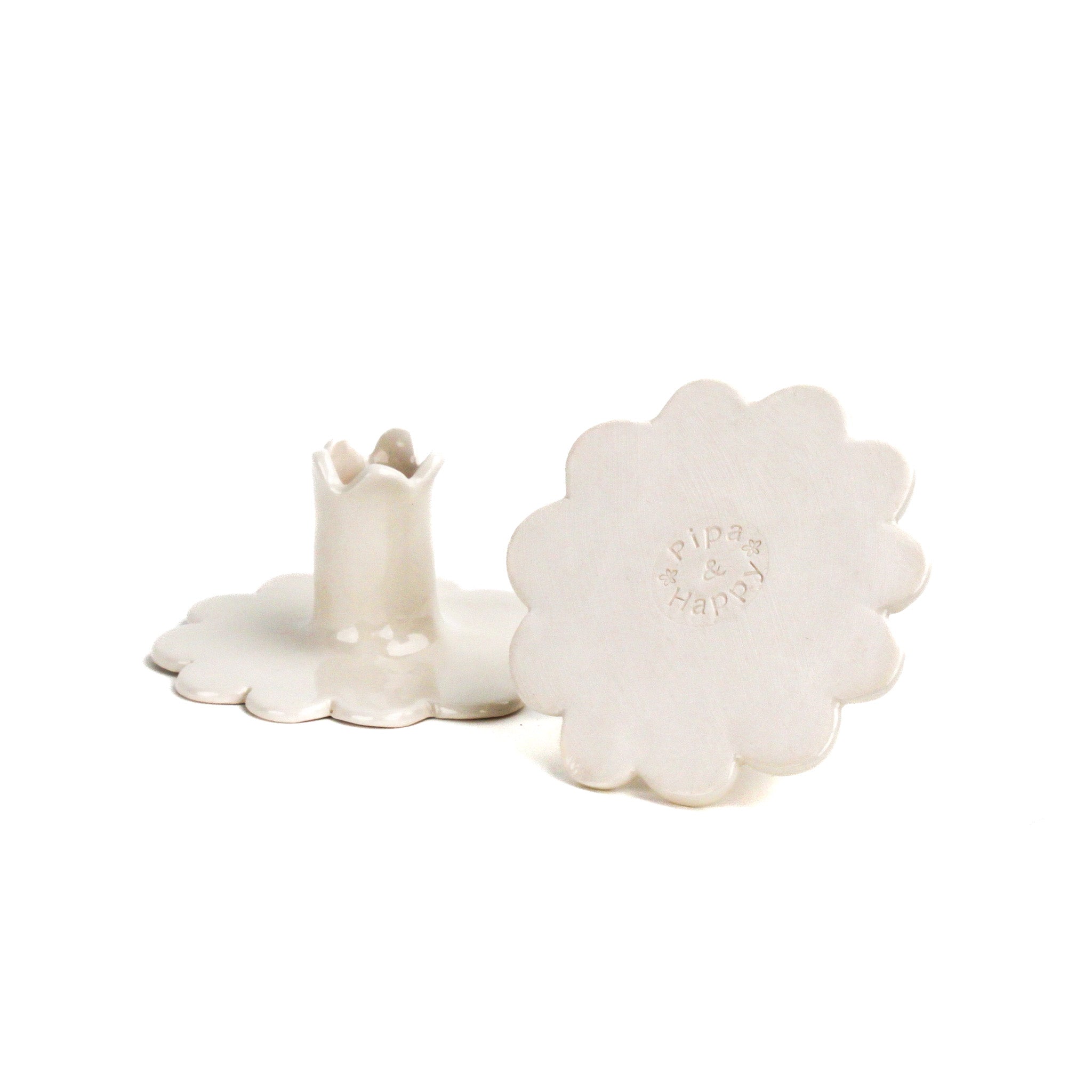 Pair of white ceramic candle holders with scalloped bases and fluted candle cups, photographed on a white background.