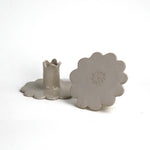 Back and bottom view of two white scalloped ceramic candle holders showing the maker’s mark.