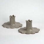 “Set of two white scalloped ceramic candle holders with flower-shaped bases.