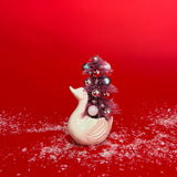a Vintage Small White Ceramic Swan w/ Pink Glitter Christmas Tree Centerpiece against a red background. 