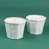 Two white textured ceramic planters with a woven-style design sitting on a green background.