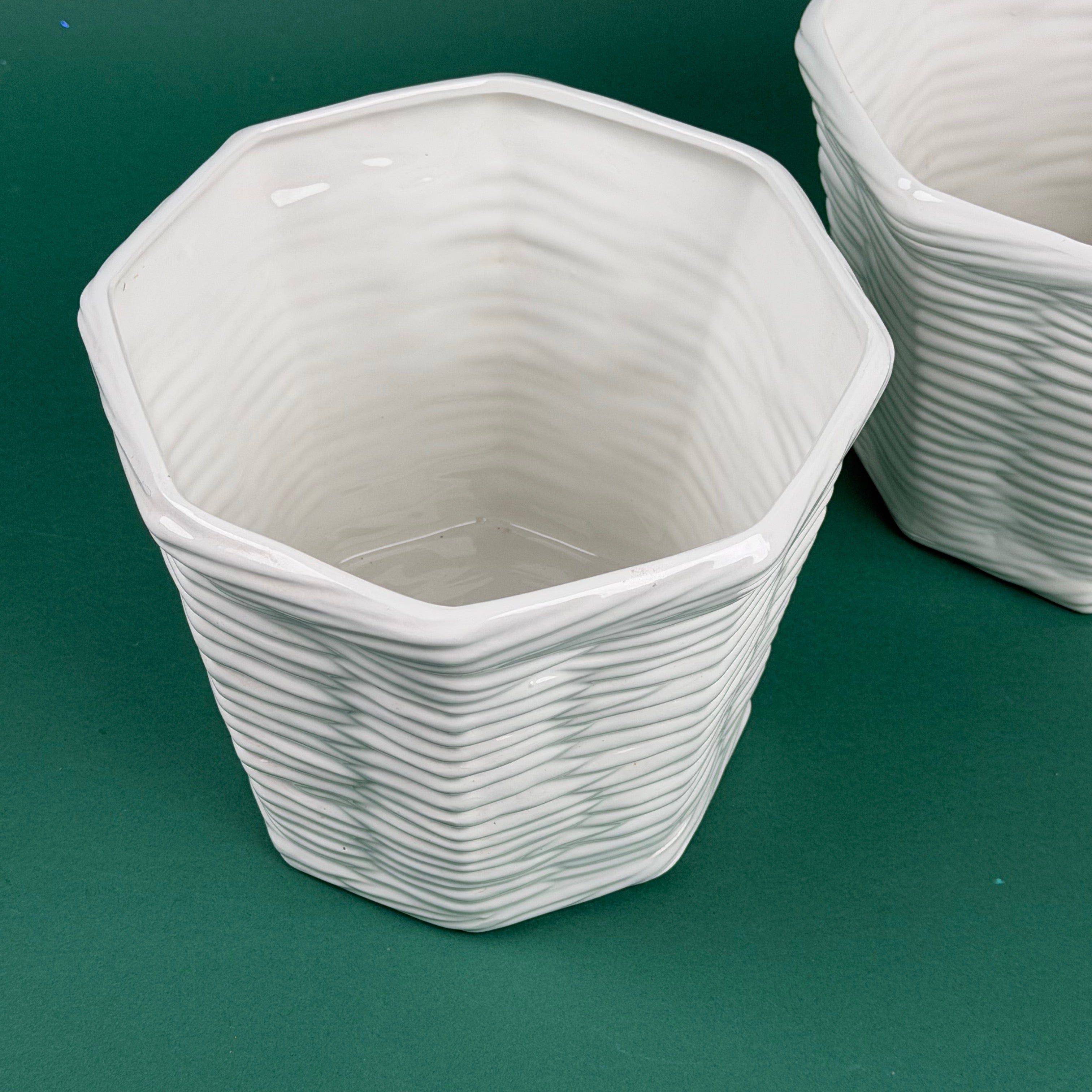 White hexagon-shaped ceramic planter with a woven textured design on a green background
