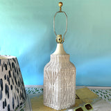 A vintage blue and white lamp featuring a white rattan base and a blue and white patterned lampshade.