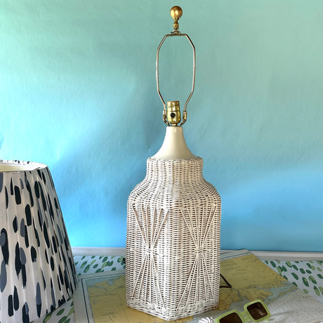 A vintage blue and white lamp featuring a white rattan base and a blue and white patterned lampshade. 