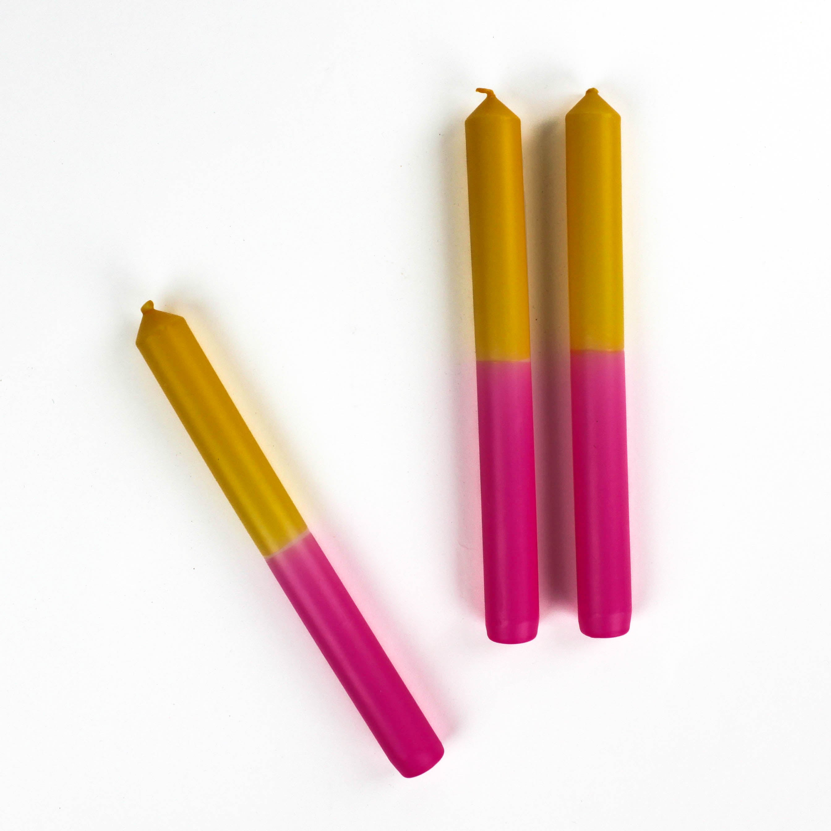 3 pink and yellow taper candles in white background