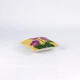 side of a Square decorative pillow with a yellow background featuring a hooked wool design of three purple pansy flowers with green stems and leaves.