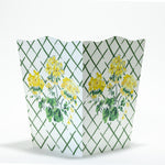 a white and green floral wastepaper basket by madcap cottage with a central yellow geranium motif. 
