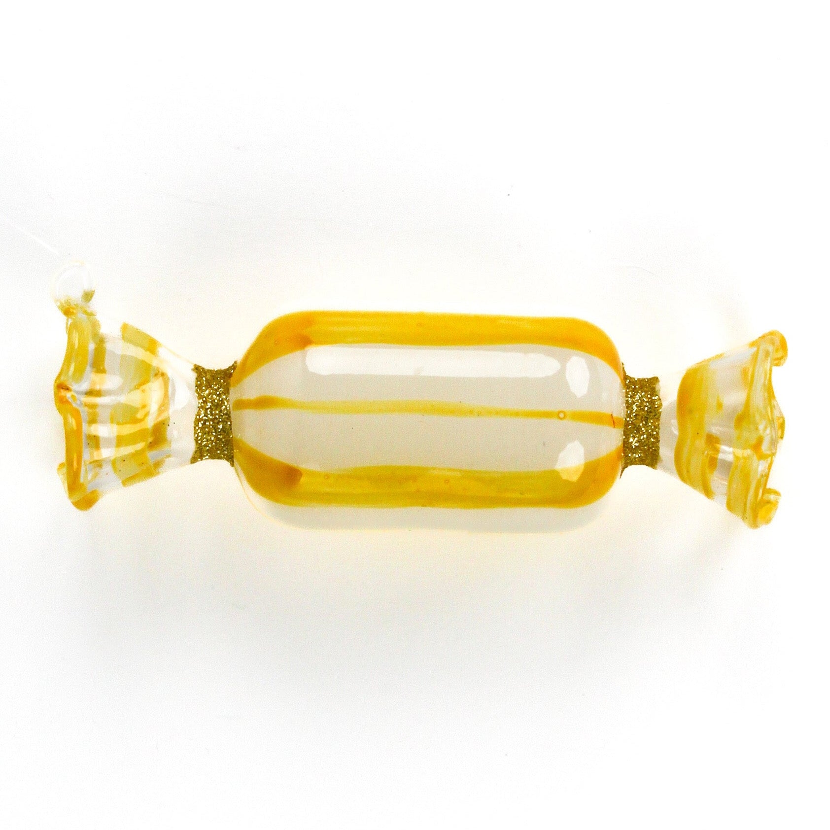 a yellow glass candy christmas ornament on a white background