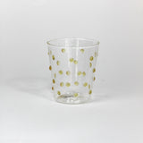 Clear glass tumbler with gold polka dots on a white background
