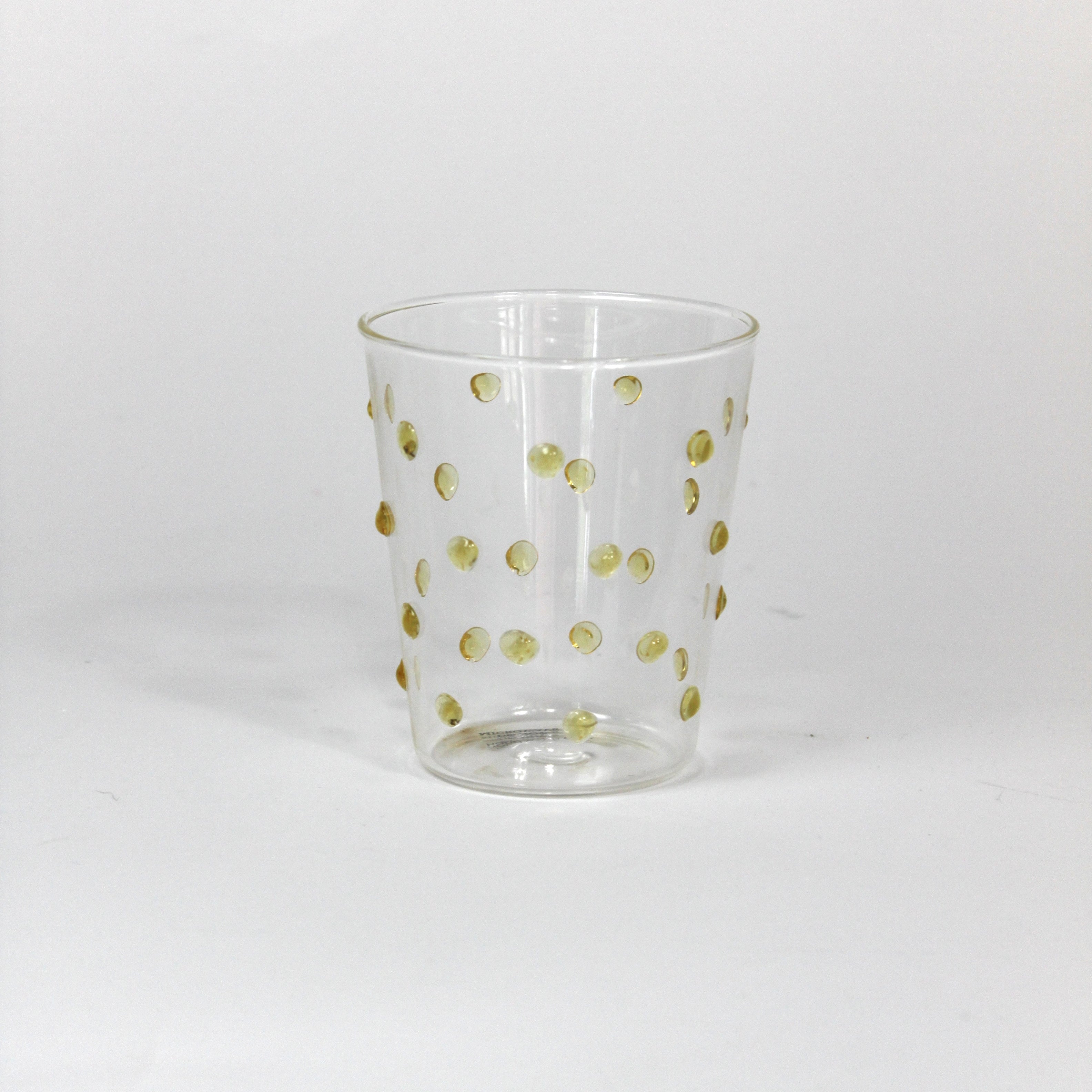 Clear glass tumbler with gold polka dots on a white background