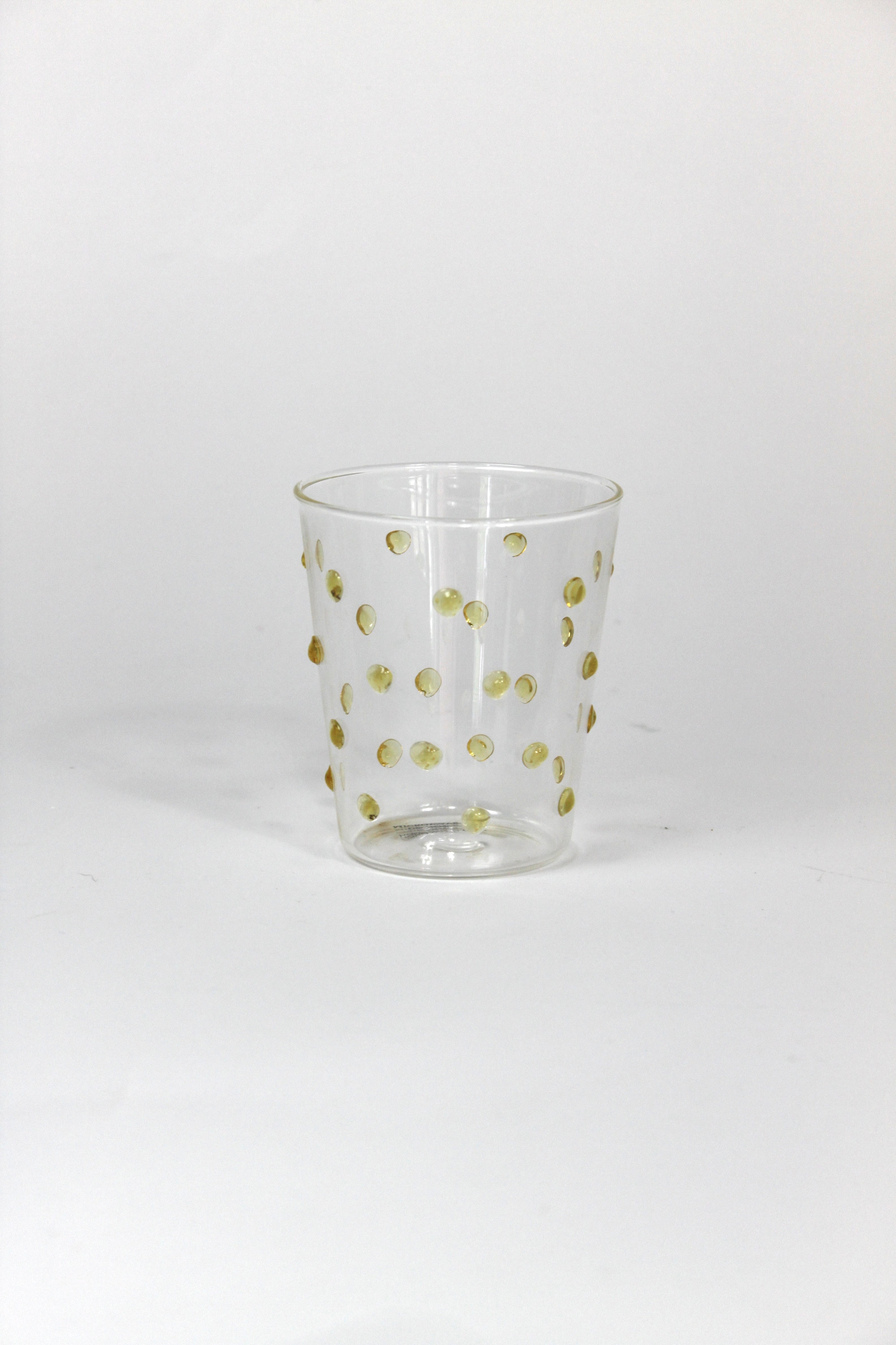 Clear glass tumbler with gold polka dots on a white background