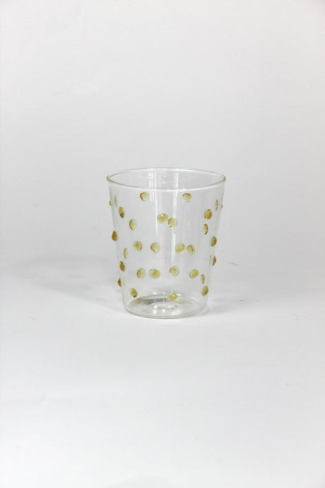 Clear glass tumbler with gold polka dots on a white background