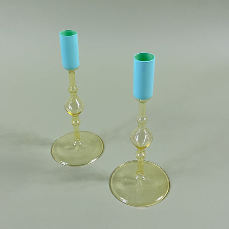 two yello glass candle holders with blue tops