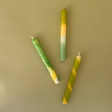 three yellow and green assorted taper candles