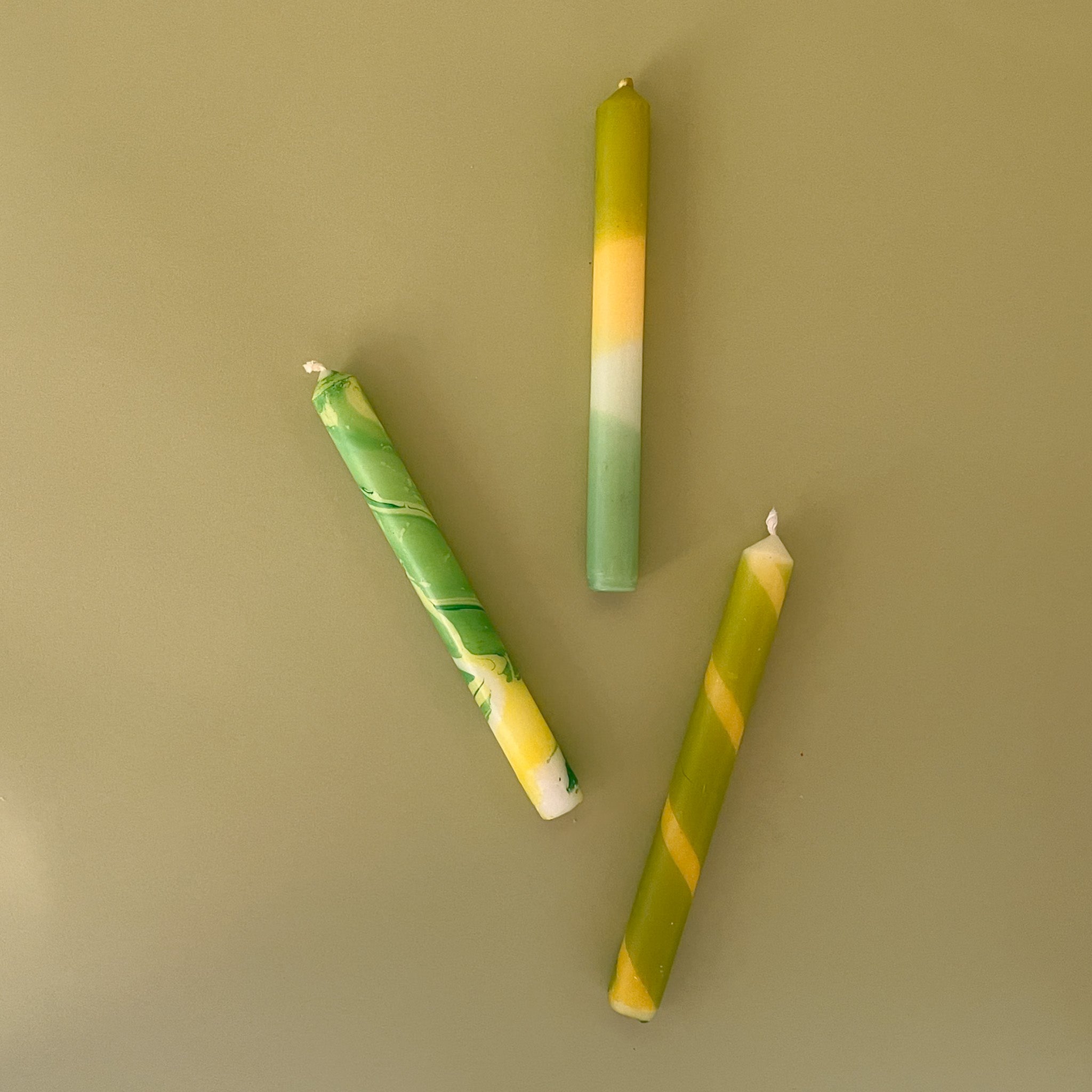 three yellow and green assorted taper candles