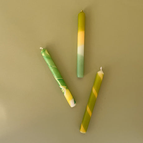 three yellow and green assorted taper candles 