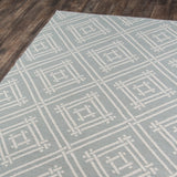 Geometric patterned area rug with white square lattice design on a wood floor, modern woven rug for living room or bedroom.
