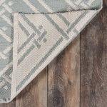 Close-up of Gray and ivory woven geometric area rug with bound edge detail on a wood floor, reversible flatweave rug.