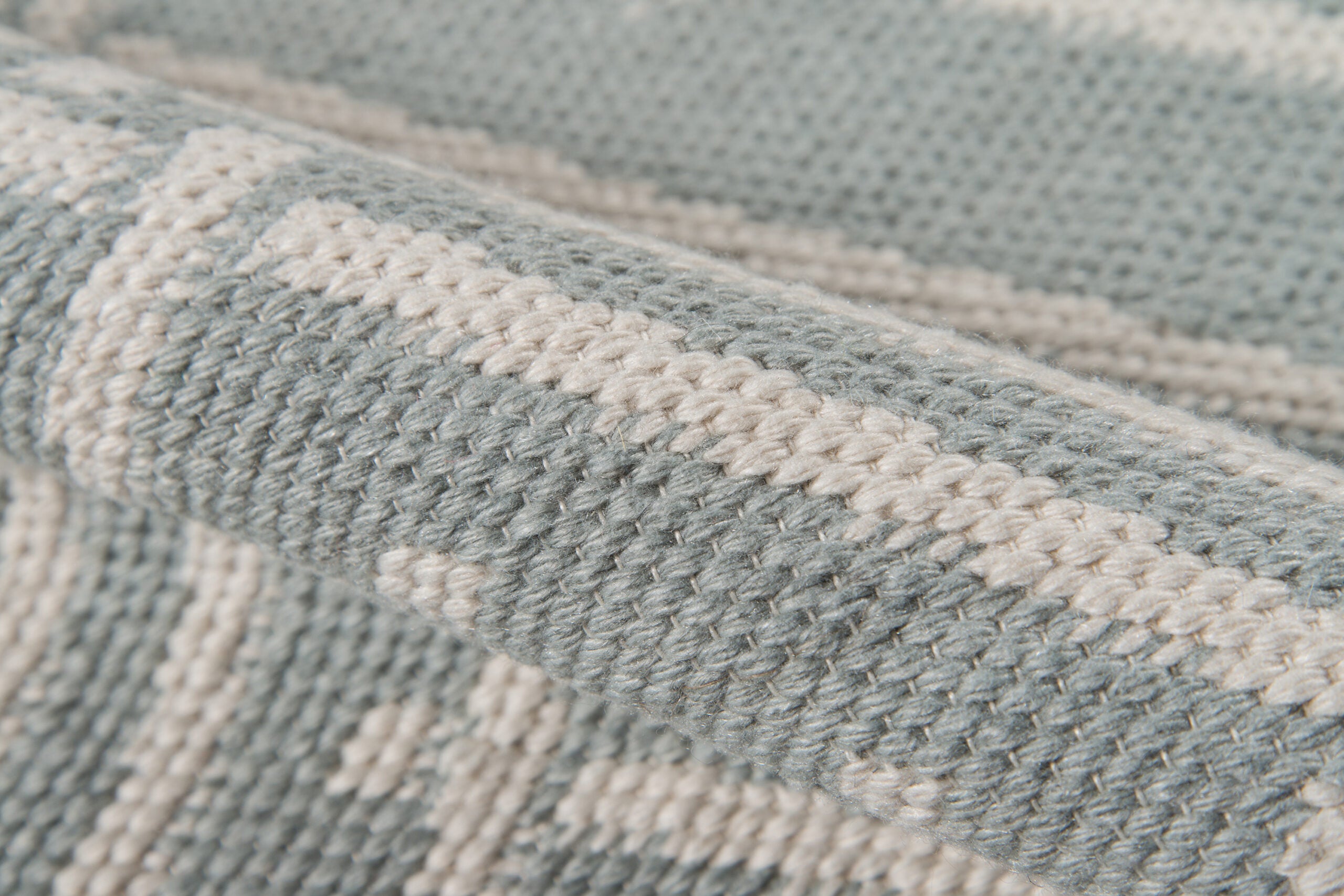 Close-up of gray area rug showing textured fabric and durable stitched weave pattern.