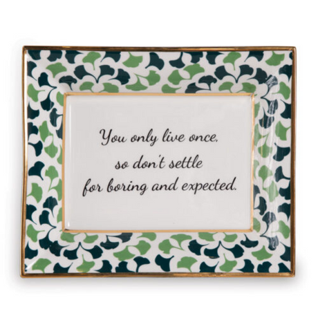 A rectangular porcelain trinket tray with a blue-and-green gingko-leaf patterned trim and gilt edging. The tray has text inside that reads 'You only live once, so don't settle for boring and expected.