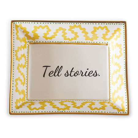 Madcap Cottage yellow and white porcelain trinket tray with a gold border and a saying that says Tell Stories. 